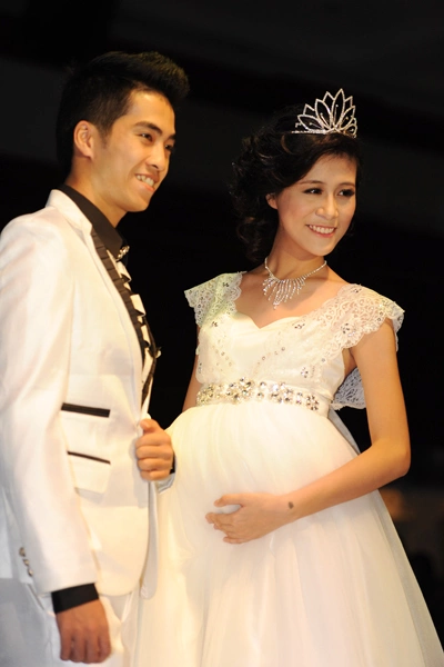 Nhà thiết kế chủ yếu tạo điểm nhấn vào phần thân trên với những hạt cườm, kim sa lấp lánh để khách mời không quá chú ý vào chiếc bụng bầu của cô dâu. Nhà thiết kế chủ yếu tạo điểm nhấn vào phần thân trên với những hạt cườm, kim sa lấp lánh để khách mời không quá chú ý vào chiếc bụng bầu của cô dâu.