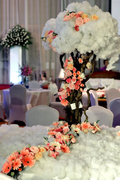Wedding planner trưng bày 3 mẫu bàn tiệc cưới. Mẫu đầu tiên là hoa kết hợp cùng cành cây khô và bông mềm mại như mây. Wedding planner trưng bày 3 mẫu bàn tiệc cưới. Mẫu đầu tiên là hoa kết hợp cùng cành cây khô và bông mềm mại như mây.