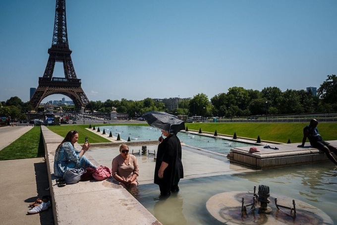 Khách du lịch giải nhiệt tại đài phun nước Trocadéro, phía trước Tháp Eiffel ở Paris vào ngày 1 tháng 7 năm 2025.
